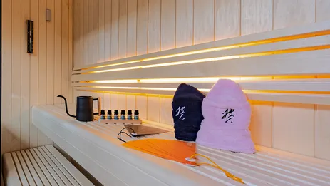 サウナベンチに置かれたアロマオイル、サウナハット、アウフグウス用の扇