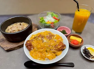 卵とじのカツ丼、小鉢、サラダ、オレンジジュースが並ぶ和食のセットメニュー