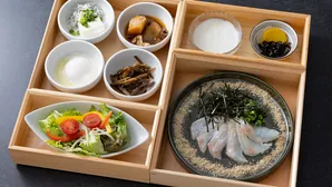 白身魚の刺身や小鉢が美しく配置された木製重箱の和朝食