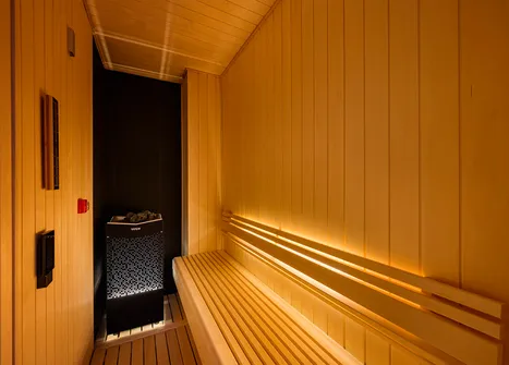 サウナストーブと間接照明が灯る木製ベンチのプライベートサウナ